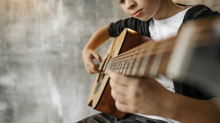 Chłopiec gra na gitarze. Widok z perspektywy zblizenia na gryf.