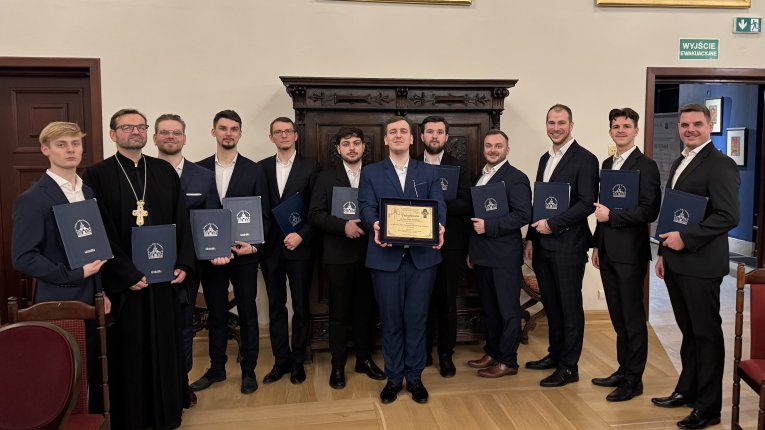 Artyści Męskiego Zespołu Muzyki Cerkiewnej „Grabarka" stoją obok siebie w sali