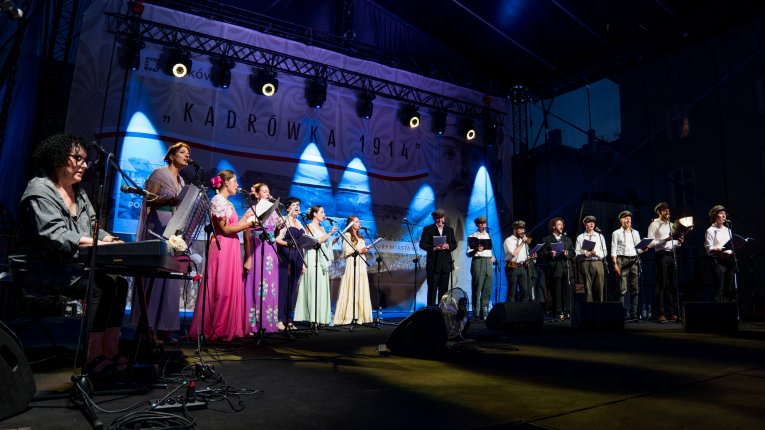 Artyści teatru Loch Camelot w strojach legionistów i dam śpiewaja pieśni patriotyczne