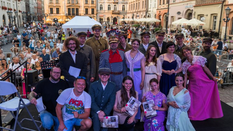 Artyści teatru Loch Camelot w strojach legionistów i dam śpiewaja pieśni patriotyczne
