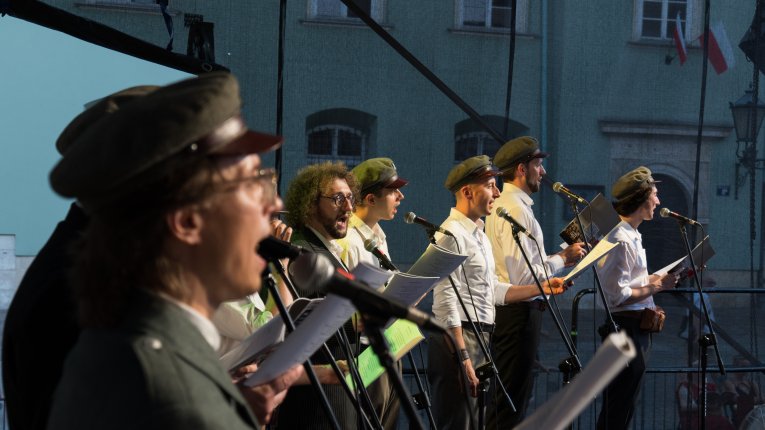 Artyści teatru Loch Camelot w strojach legionistów i dam śpiewaja pieśni patriotyczne