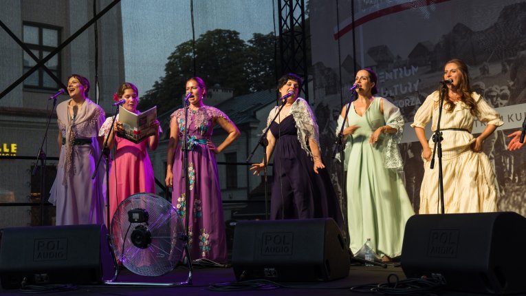Artyści teatru Loch Camelot w strojach legionistów i dam śpiewaja pieśni patriotyczne